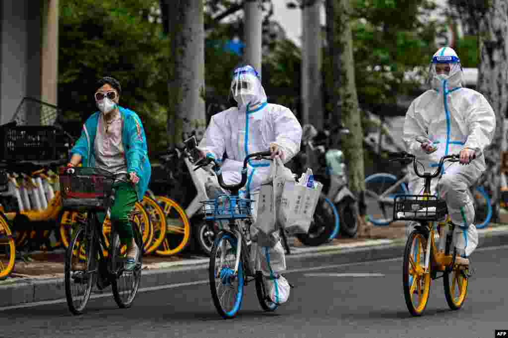 Workers wearing personal protective equipment (PPE) cycle on a street during a Covid-19 coronavirus lockdown in the Jing'an district of Shanghai, China.