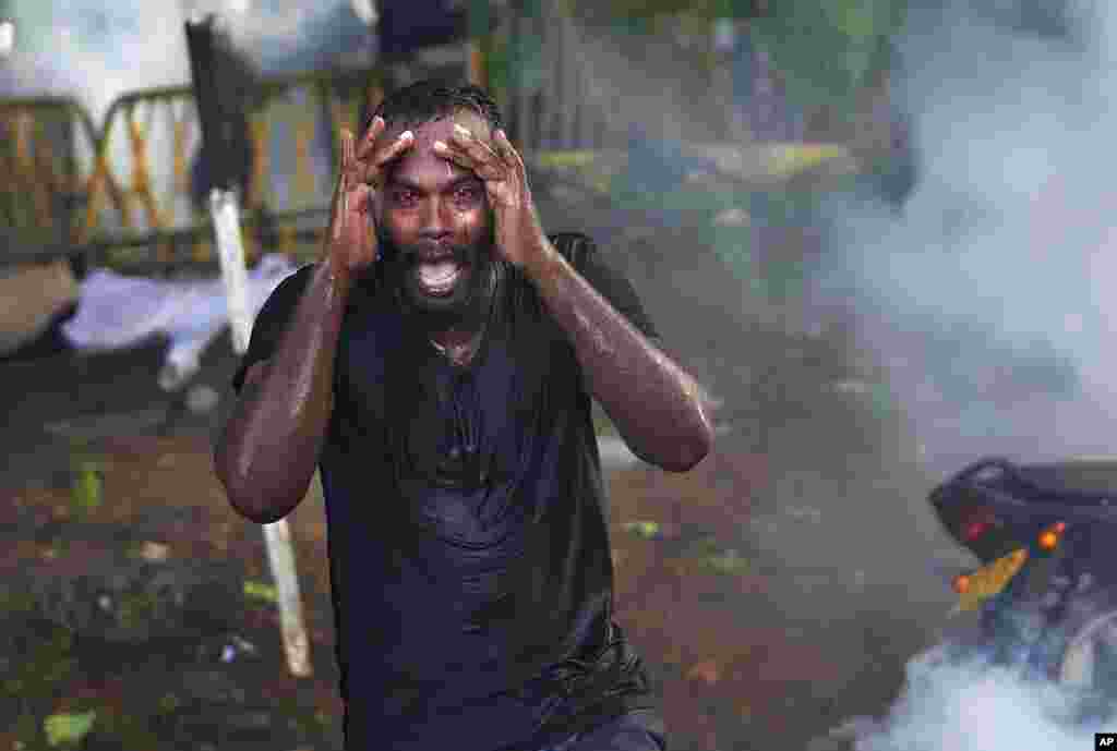 An injured protester grieves in pain as police fire tear gas to disperse protesting members of the Inter University Students Federation during an anti-government protest in Colombo, Sri Lanka. 