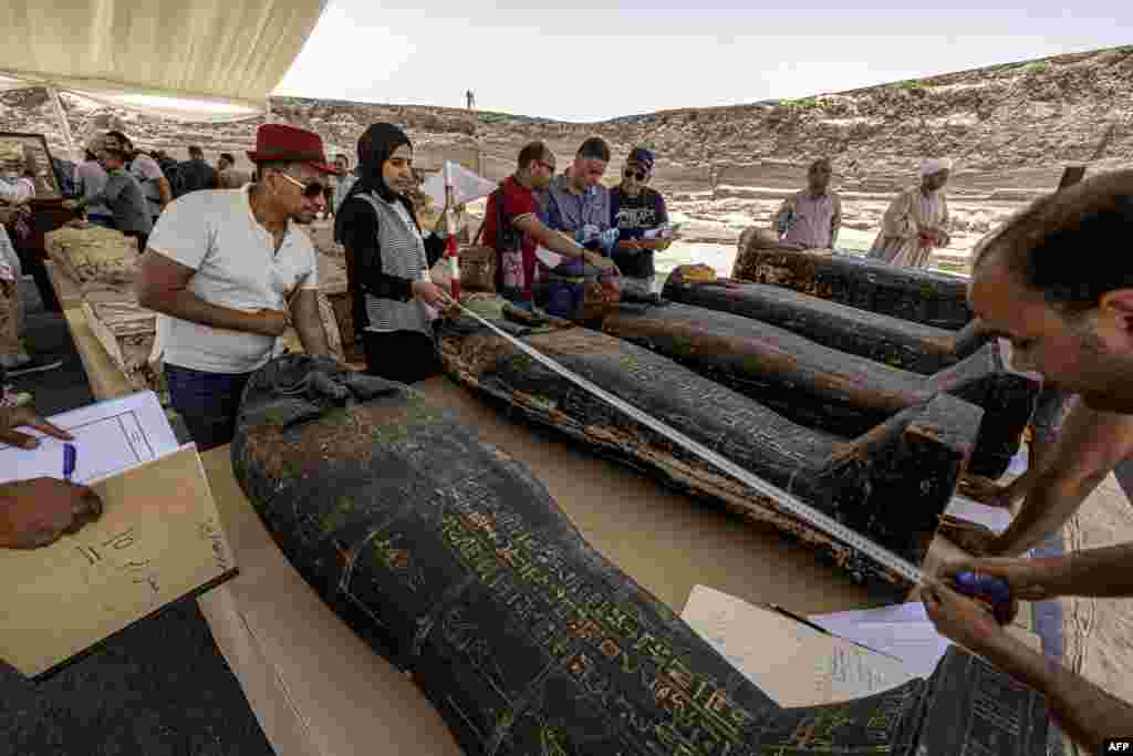 Archaeologists measure the length to register one of the sarcophaguses found in a cache dating to the Egyptian Late Period (around the fifth century B.C.), discovered by a mission headed by Egypt's Supreme Council of Antiquities, at the Saqqara necropolis, southwest of Egypt's capital.