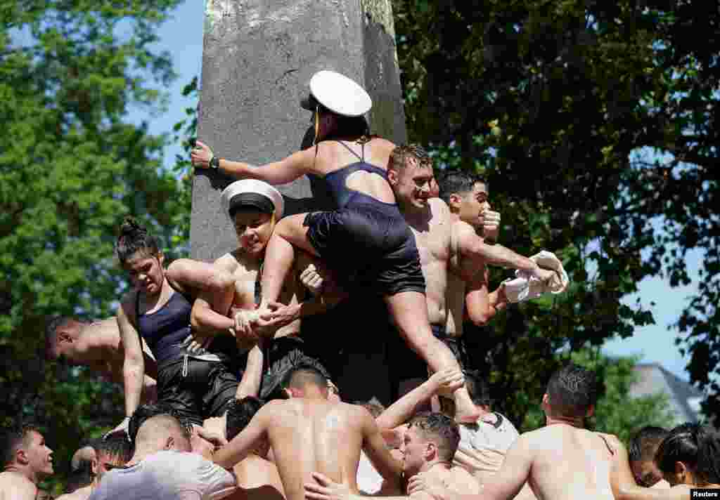 Plebes form a human pyramid to place an upperclassman hat atop the 21-foot vegetable shortening-covered Herndon Monument, a tradition marking the end of their plebe year at the U.S. Naval Academy in Annapolis, Maryland, May 23, 2022.