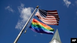 ธงชาติสหรัฐฯ คู่กับธงสัญลักษณ์ความหลากหลายทางเพศ ที่หน้าโบสถ์ Asbury United Methodist Church เมือง Prairie Village รัฐเเคนซัส 19 เม.ย. 2019