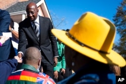 FILE - Sen. Raphael Warnock, D-Ga., shakes hands at a rally before walking to cast his early vote Nov. 27, 2022, in Atlanta, in his runoff election against Republican Herschel Walker.
