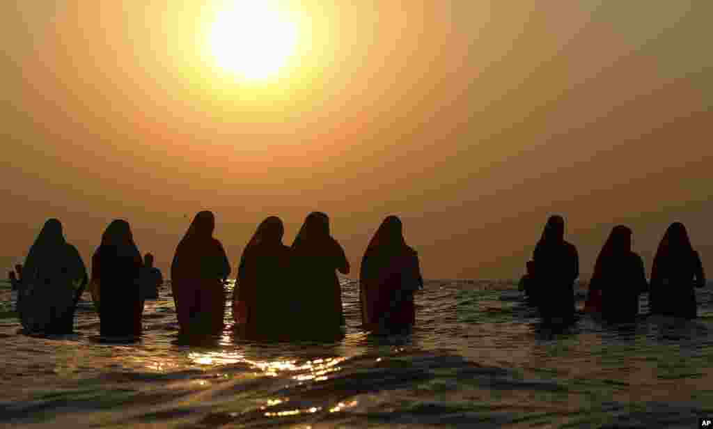 Hindu devotees offer prayers in the waters of the Arabian Sea at sunset during Chhath Puja festival in Mumbai, India.