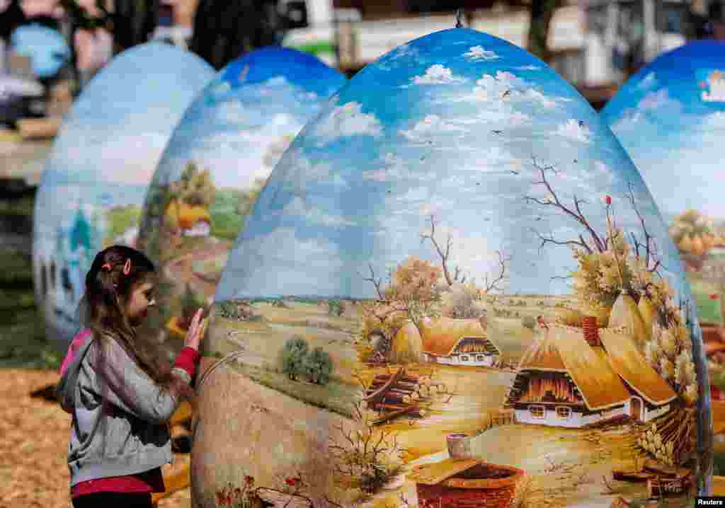 A girl looks at two-meter-high Easter eggs painted in the traditional art style in Koprivnica, Croatia.