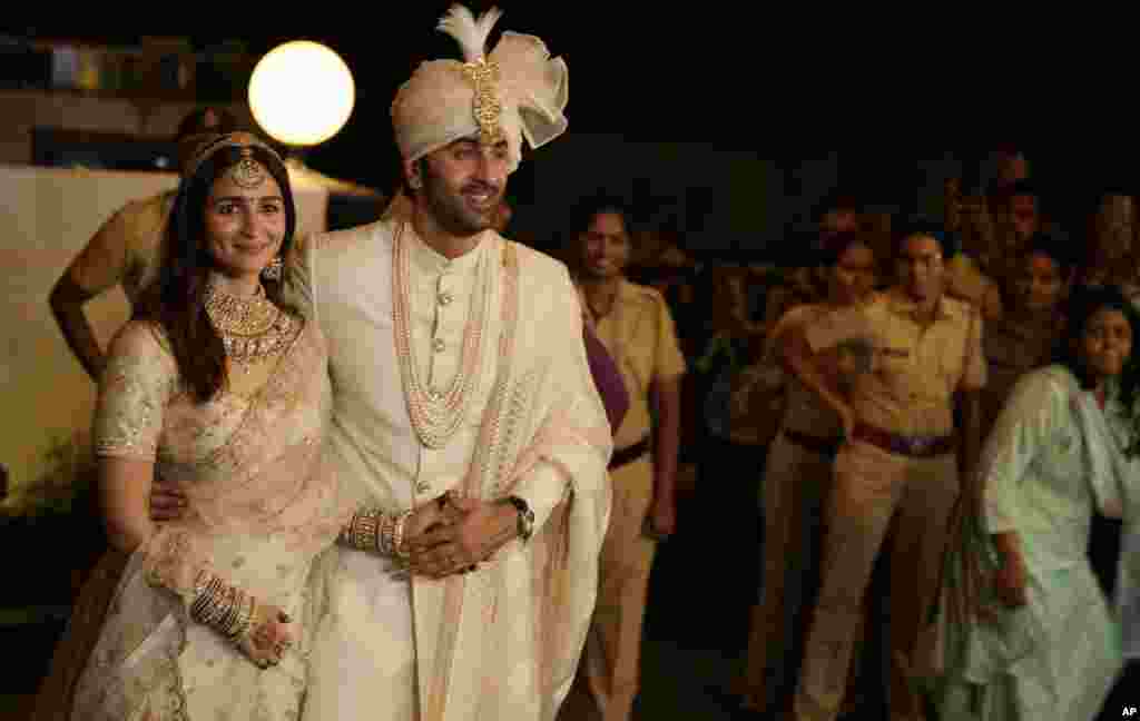 Bollywood actors Ranbir Kapoor and Alia Bhatt, left, pose for photographs after their wedding outside their residence in Mumbai, India.