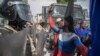A protester with colors of the Russian national flag painted on his body argues with police in front of the U.S. Embassy during a protest to reject an international military force requested by the government, in Port-au-Prince, Haiti, Oct. 17, 2022.