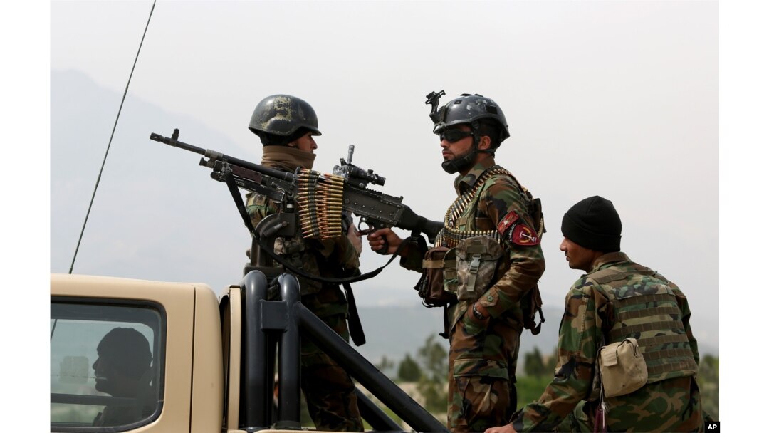 FILE - Afghan military soldiers stand stand alert at the entrance gate of the new parliament building after a rocket attack in Kabul, Afghanistan.