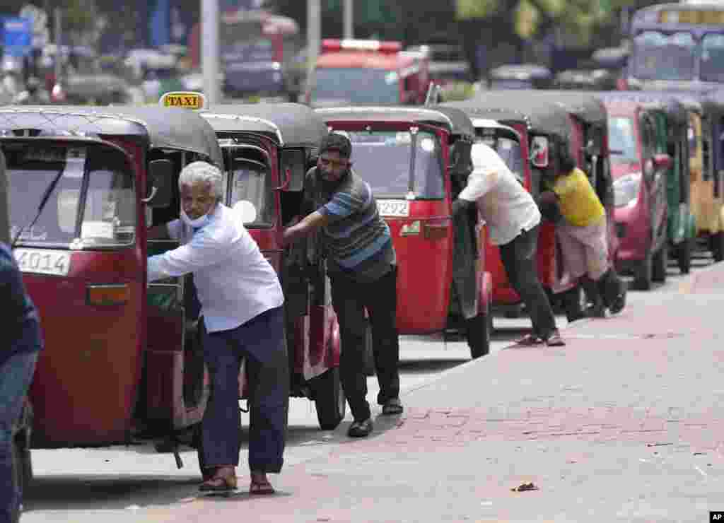 Sri Lankan auto rickshaw drivers queue up to buy petrol near a fuel station in Colombo.