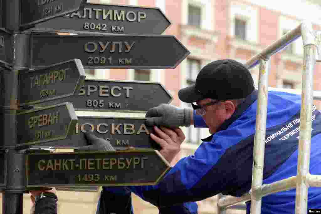 Workers remove plates directing to Russian cities from a street sign in Odesa, Ukraine, amid Russia's invasion of Ukraine.