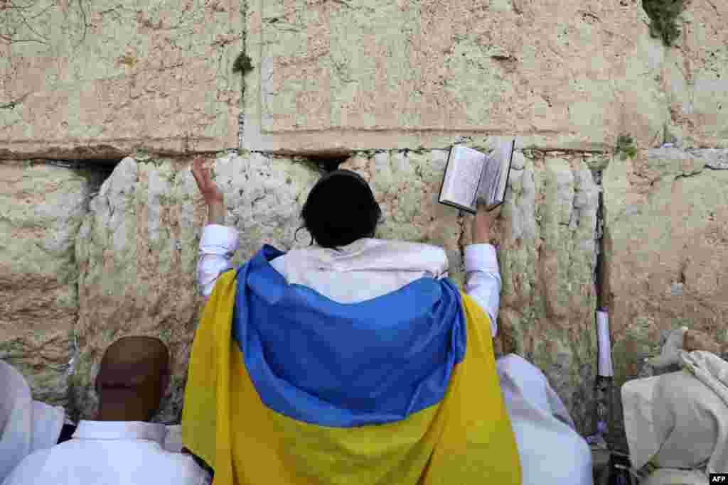 A Jewish worshipper drapped in a Ukranian flag, takes part in the Cohanim prayer (priest's blessing) during the Passover holiday at the Western Wall in Jerusalem's Old City.
