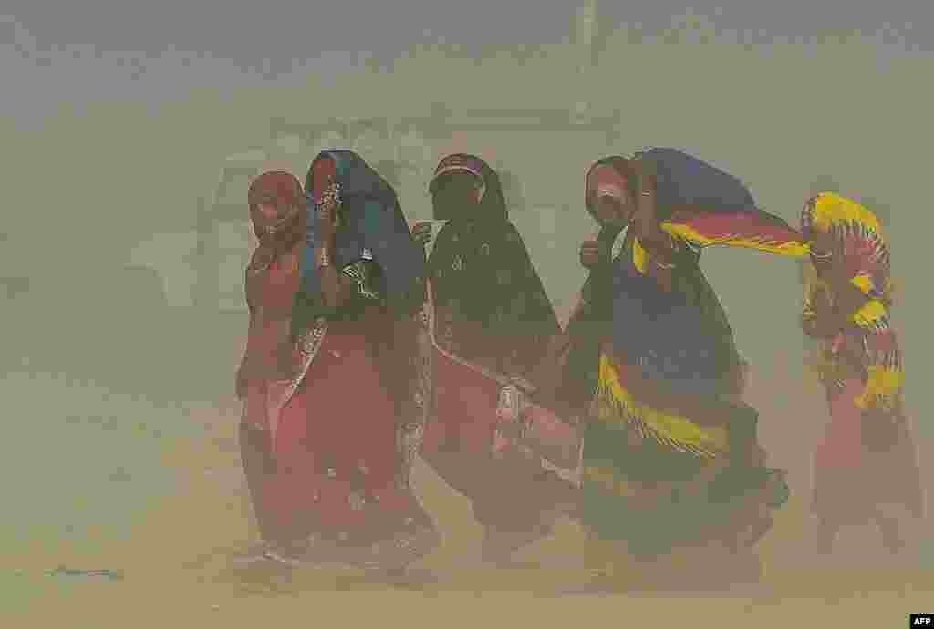 People walk through a sand storm at the Sangam, the confluence of the rivers Ganges, Yamuna and mythical Saraswati in Allahabad, India.