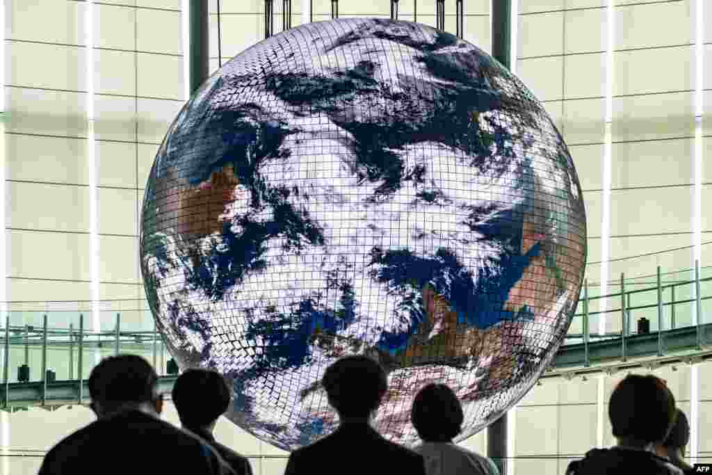 Reporters look at the Geo-Cosmos, the world's first spherical display made of organic electroluminescent panels showing a high-resolution model of the Earth, with 10,362 LED panels during a media preview at the Miraikanon, the National Museum of Emerging Science and Innovation in Tokyo, Japan.