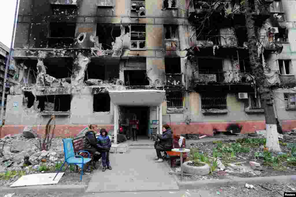 Local residents gather outside a residential building heavily damaged during Russia's invasion of Ukraine, in the southern port city of Mariupol.