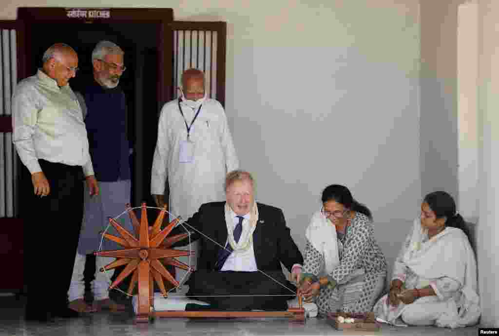 Britain's Prime Minister Boris Johnson spins cotton on a wheel during his visit to the Sabarmati Ashram in Ahmedabad, India.