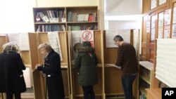 Voters make their decision at a polling station in North Dublin as voting gets under way in the general election in Dublin, Ireland, Feb. 8, 2020. 