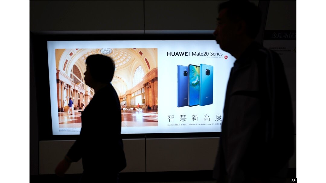 People walk past an advertisement for Huawei at a subway station in Hong Kong, Dec. 5, 2018.