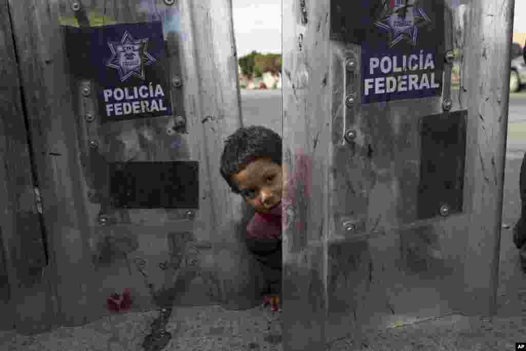 Elias Lopez, a three-year-old Honduran migrant, plays in between the shields of a line of Mexican riot police, when the group he was part of tried to cross the Chaparral border crossing in Tijuana, Mexico, Nov. 22, 2018.