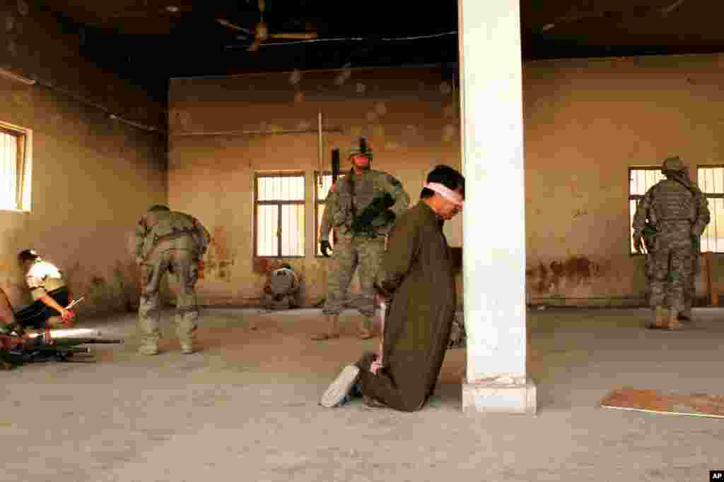 A U.S. soldier guards an arrested man after a gunfight in central Baqouba, Iraq, March 29, 2007.
