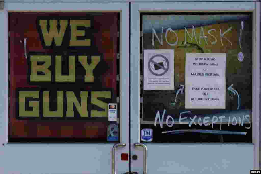 A sign on the door warning customers not to wear a face mask reads "We Draw Guns on Masked Visitors" at the 619DW Guns and Ammo store in Merrimack, New Hampshire, Nov. 29, 2021.