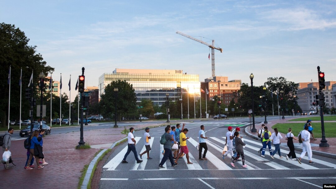 Migrantes cruzan Massachusetts Avenue hacia Union Station, cerca del Capitolio de EEUU, en Washington DC, después de completar un viaje en autobús desde Texas, el 30 de julio de 2022.