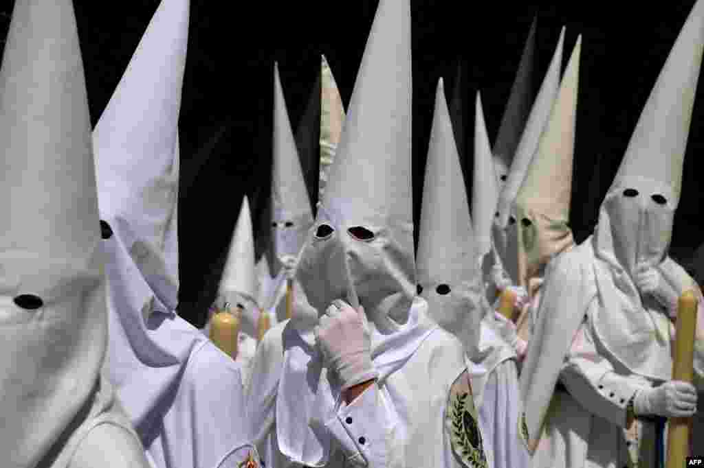 Penitents of 'La Paz' brotherhood parade during the Holy Week's Palm Sunday procession in Seville, Spain.