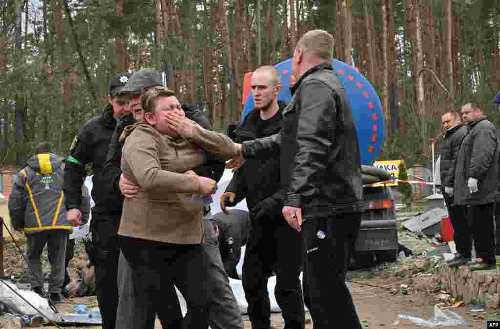 A Ukrainian mother reacts after the body of her son was discovered in a manhole at a petrol station in the outskirts of the Buzova village, west of Kyiv. At least two bodies, appearing to be clad in a mix of civilian and military clothing, were discovered in a manhole at the back of a destroyed motorway petrol station. 
