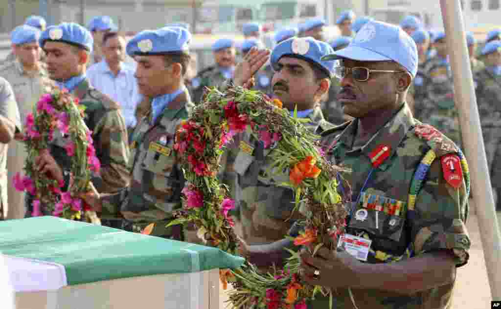 Nesta foto enviada pela Missão das Nações Unidas no Sudão do Sul (UNMISS), o Estado-Maior General das Forças Armadas Delali Sakyi do Gana põe flores nos caixões dos dois colegas que morreram na passada quinta-feira