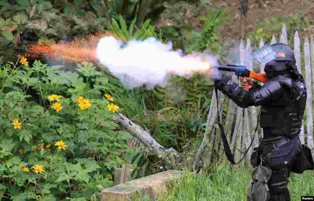 A riot policeman fires teargas at indigenous protesters who have blocked the Pan-American Highway in Mondomo, Colombia, Oct. 17, 2013. Hundreds of indigenous protesters blocked the Pan-American Highway between Cali and Popayan, demanding certain agreements they say the government is not fulfilling, such as the right to land ownership, health and education reforms, reported local media.