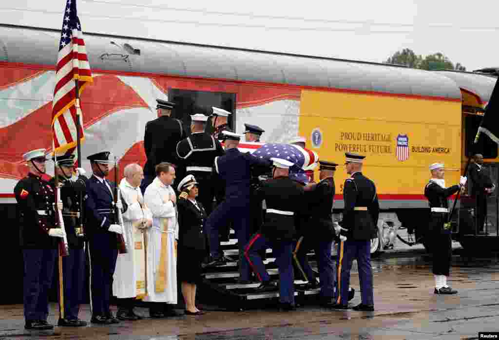 The flag-draped casket of former President George H.W. Bush is carried by a joint services military honor guard in Spring, Texas, as it is placed on a Union Pacific train. The train will take about 2 hours to travel roughly 70 miles (113 kilometers) to the city of College Station, home to Bush's presidential library at Texas A&M University. The locomotive has been painted the colors of the Air Force One plane used during his presidency and bears the number "4141" in honor of the 41st president. 