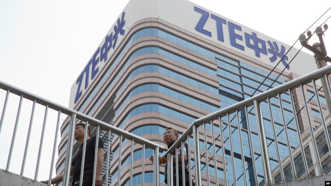 Men pass by a building of Chinese tech giant ZTE in Beijing, China, May 8, 2018.