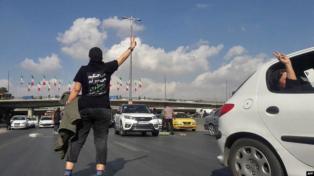 FILE - This UGC image posted on Twitter on Nov. 3, 2022, shows a person, wearing a shirt that translates from Persian to "We will fight, we will die, we will take back Iran," in the middle of a busy highway in the city of Karaj, Iran, near Tehran. 
