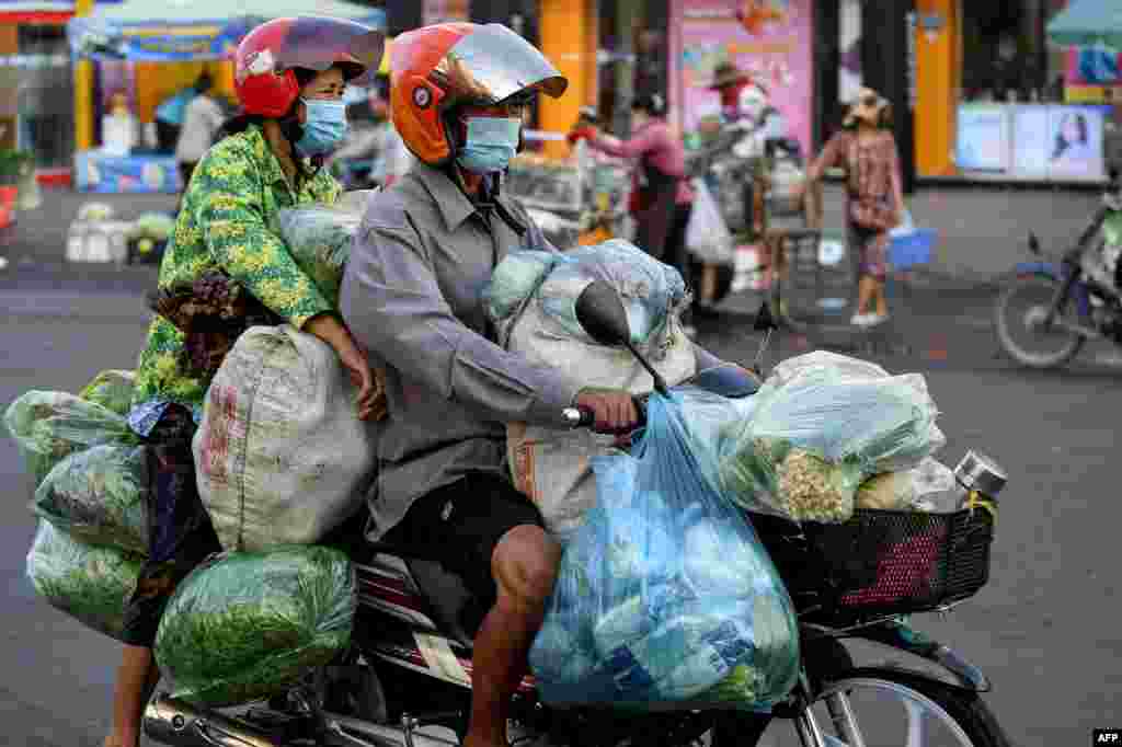 A couple transports vegetables on a motorcycle in Phnom Penh, Cambodia.