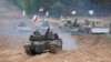 FILE - Military vehicles and tanks of Poland, Italy, and the United States move during NATO military exercises at a training ground in Kadaga, Latvia, Sept. 13, 2021.