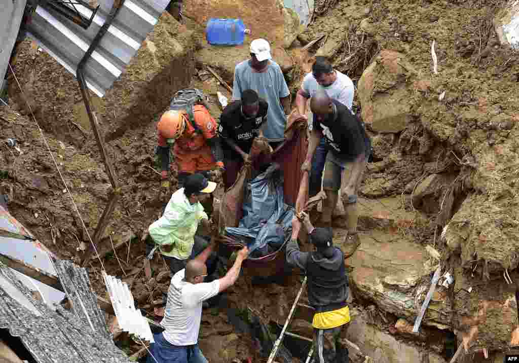 People carry a victim's body out of the rubble after a mudslide in Petropolis, Brazil. Large scale flooding destroyed hundreds of properties and claimed at least 34 lives in the area.