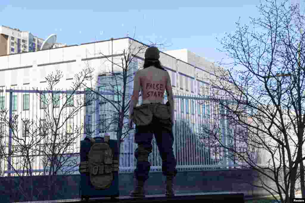 An activist of women's rights group Femen stages a protest outside the U.S. Embassy demanding American diplomats not to leave the city in Kyiv, Ukraine.