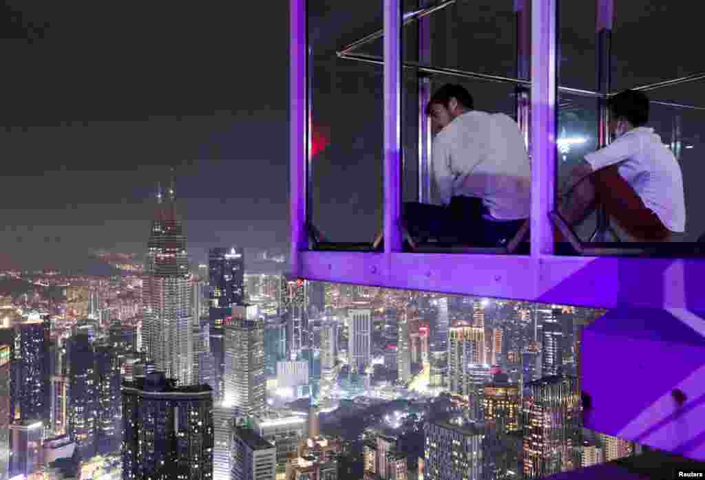 Visitors of the Kuala Lumpur Tower look at the skyline, including Malaysia's landmark Petronas Twin Towers, after the lights were turned off to mark Earth Hour, in Kuala Lumpur.