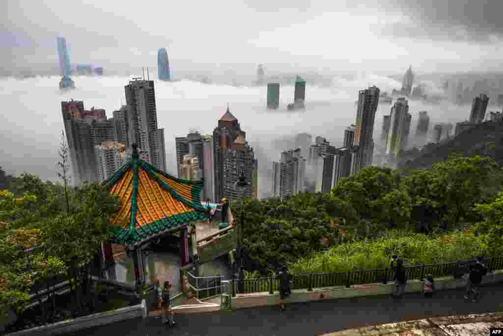 People watch fog shrouding commercial buildings in Hong Kong at the Peak viewpoint.