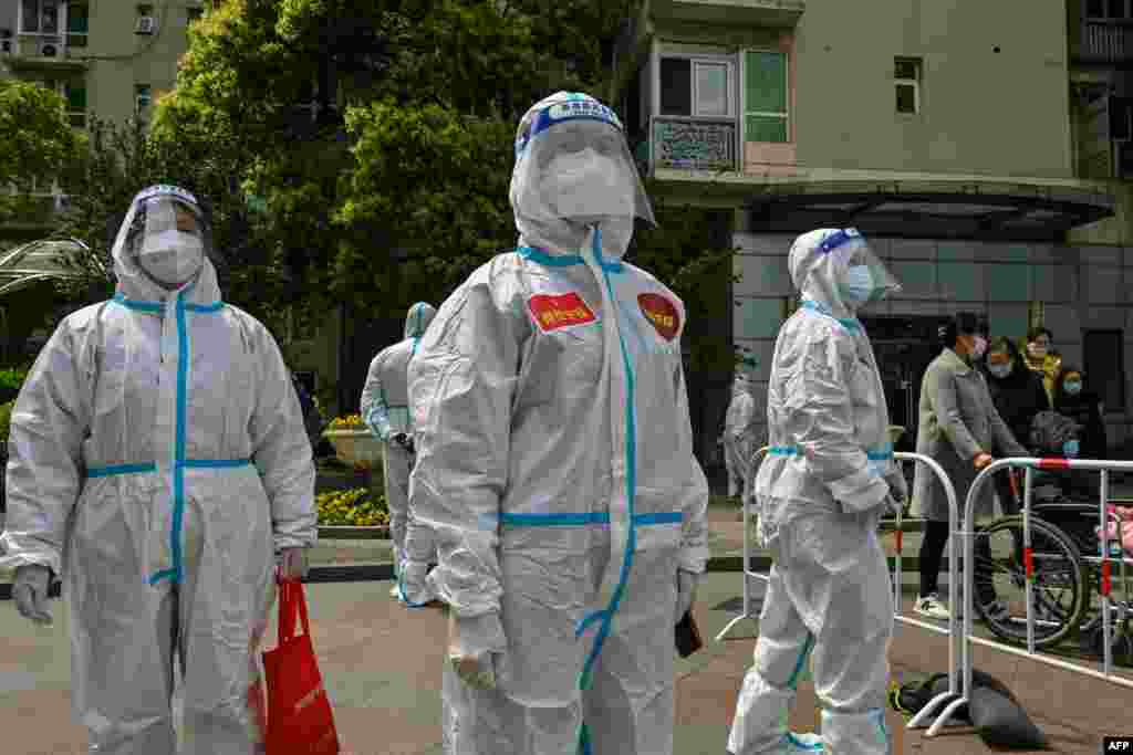 Workers and volunteers look on in a compound where residents are tested for the COVID-19 coronavirus during the second stage of a pandemic lockdown in Jing' an district in Shanghai.