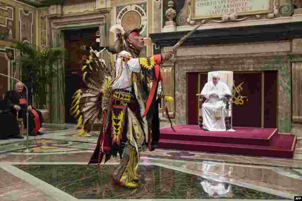 A member of Canada's Indigenous delegations dances in front of Pope Francis at the Vatican. Pope Francis apologized for the decades of abuse at church-run residential schools in Canada, and said he would visit the country in late July. (Vatican Media / AFP)
