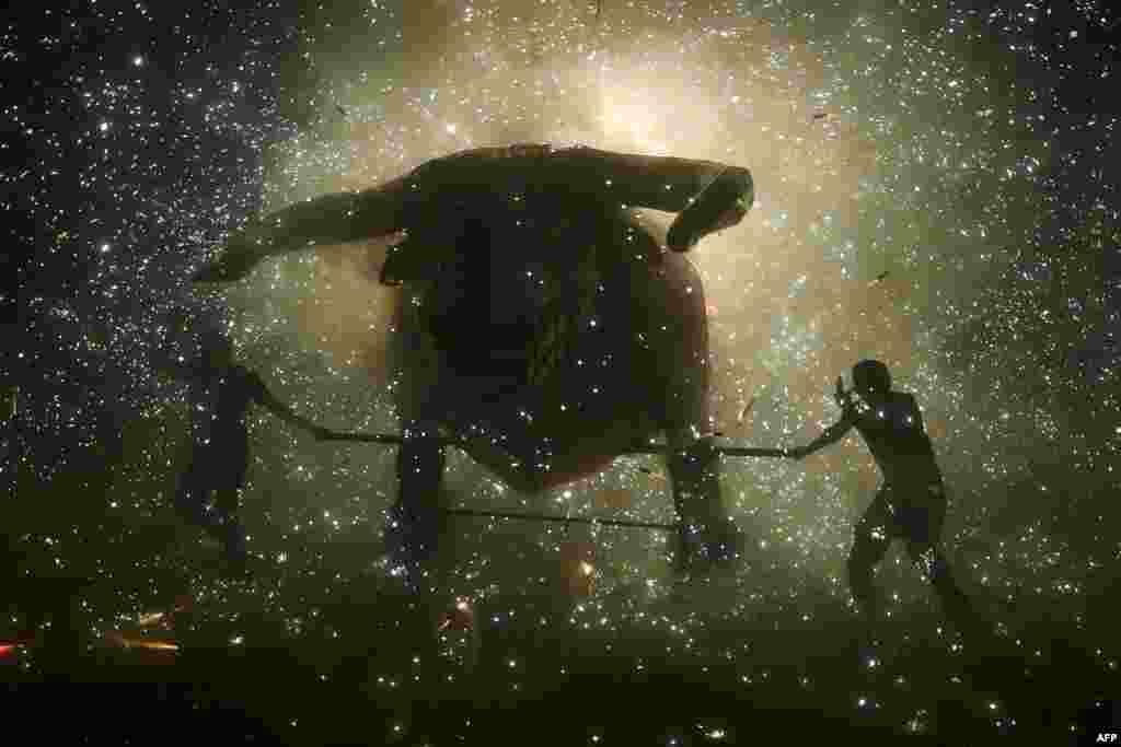 People stand beneath the sparks of fireworks beside the traditional "torito" (little bull) made of paper and wood during celebrations of San Juan de Dios in Tultepec, on the outskirts of Mexico City, March 8, 2022.