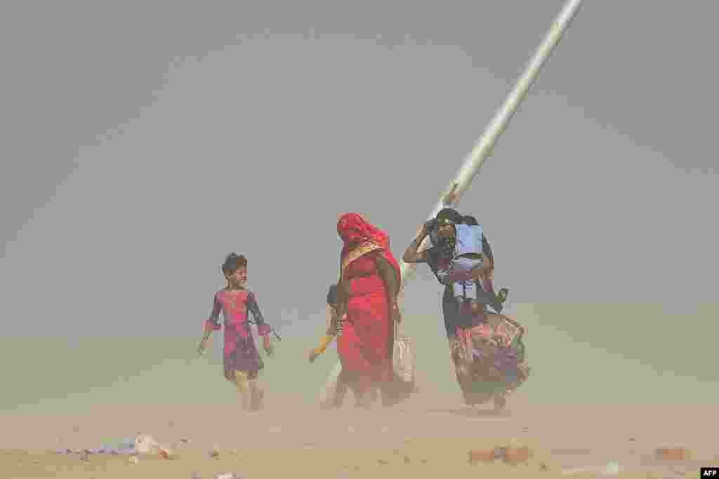 Women walk during a dust storm at the Sangam, the confluence of the Ganges, Yamuna and mythical Saraswati Rivers, in Allahabad, India.