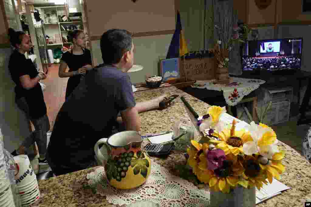 Dmytro Kovalenko (foreground), manager of Ukrainian restaurant Streecha in New York, and employees watch Ukrainian President Volodymyr Zelenskyy deliver a virtual address to the U.S. Congress.