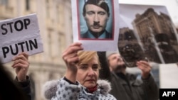 ARCHIVO - Una manifestante sostiene una foto que muestra al presidente ruso Vladimir Putin con los rasgos de Adolf Hitler durante una manifestación contra la invasión rusa de Ucrania, en Skopje, Macedonia del Norte, el 6 de marzo de 2022.