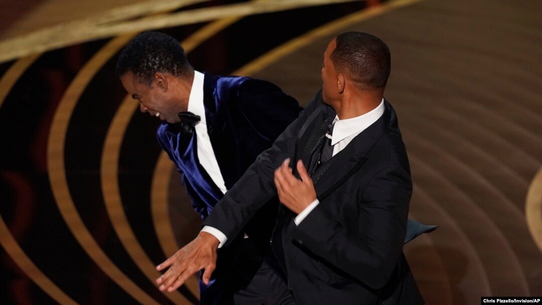 FILE - Will Smith, right, hits presenter Chris Rock on stage at the Oscars, at the Dolby Theatre in Los Angeles, March 27, 2022.