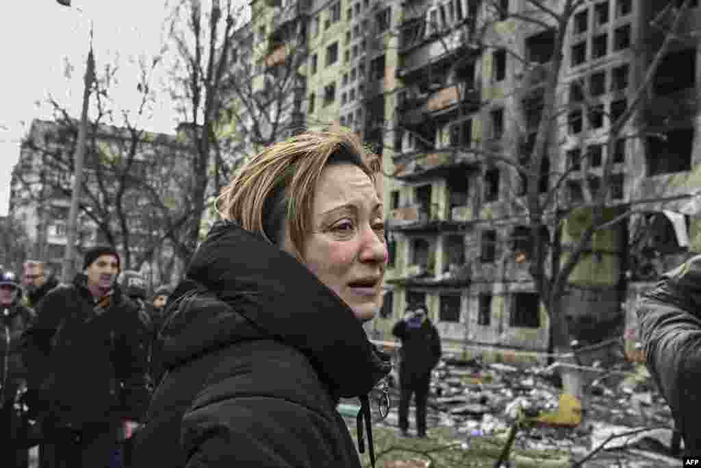 A woman reacts as she stands outside destroyed apartment blocks following Russian shelling in the northwestern Obolon district of Kyiv. Two people were killed as various neighborhoods of the Ukraine capital Kyiv came under shelling and missile attacks, city officials said, after the Russia's military invaded the Ukraine on Feb. 24, 2022.