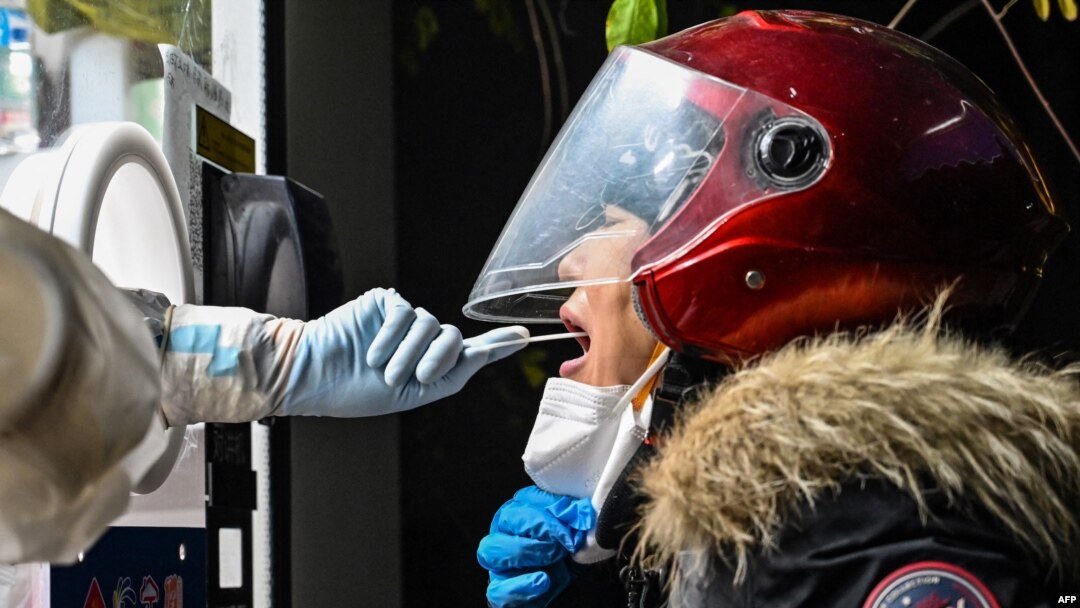 A health worker takes a swab sample from a woman to test for the COVID-19 coronavirus in the Jing'an district in Shanghai, China, on Dec. 23, 2022. 