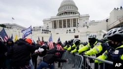 ARCHIVO - Insurrecciones violentas leales al presidente Donald Trump atraviesan una barrera policial en el Capitolio de Washington.