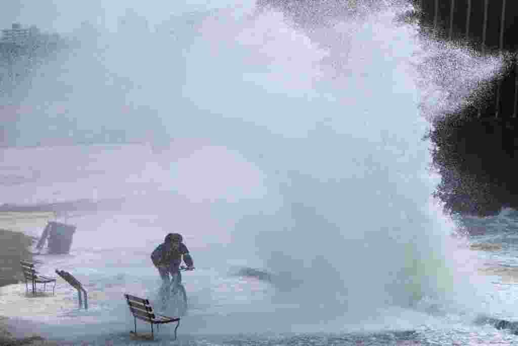 A man rides a bicycle along the sea wall after rainstorms lashed the western Canadian province of British Columbia in Vancouver, Nov. 15, 2021.