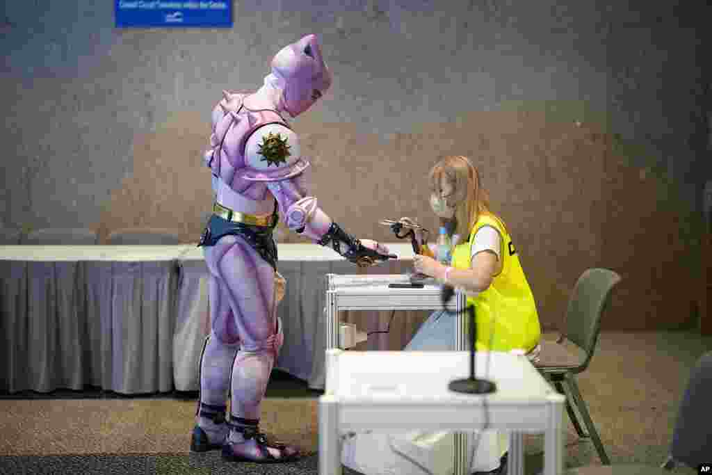 A participant wearing his cosplay featuring an animated character gets his government contact tracing QR code in the "LeaveHomeSafe" COVID-19 mobile app scanned at Ani-Com and Games exhibition in Hong Kong.
