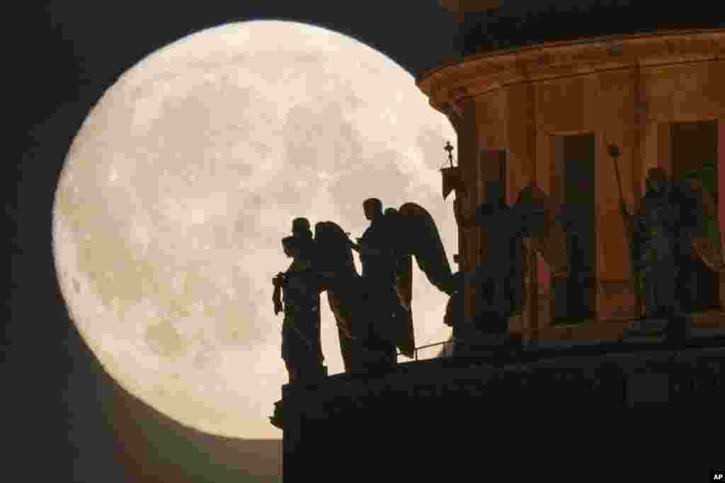 Sculptures of angels at the St. Isaak's Cathedral are silhouetted on the full moon in St. Petersburg, Russia, June 13, 2022.